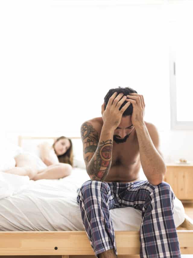 Upset-man-sitting-bed-front-his-wife